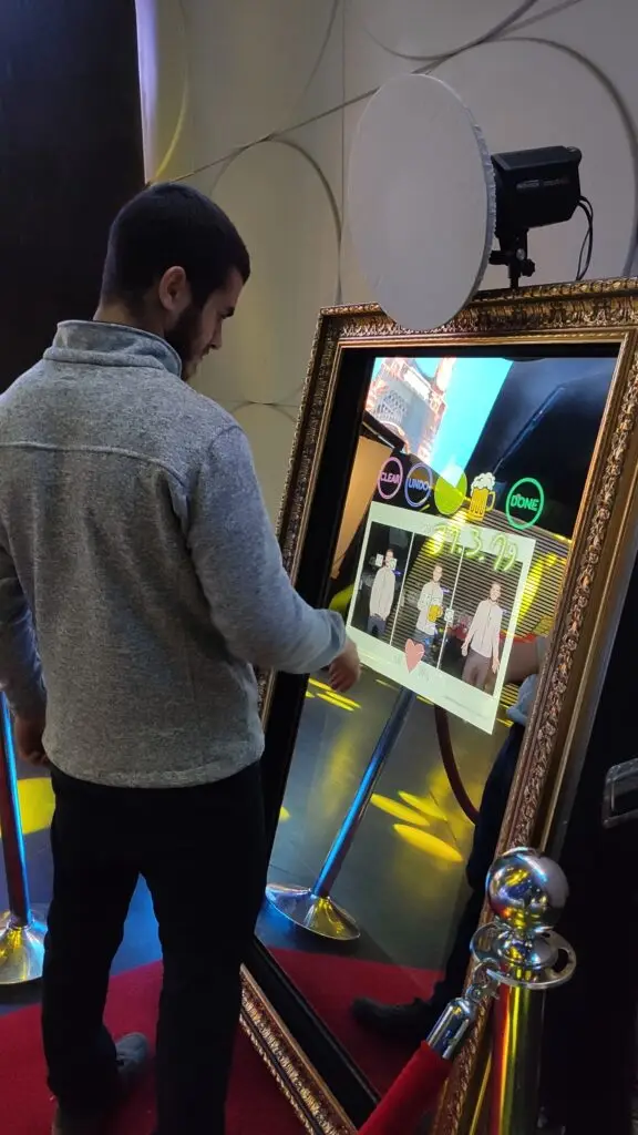 A man toggling with the features on a Magic Mirror Photo Booth, a full-length mirror and camera system